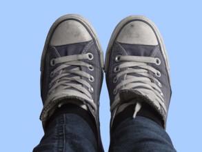 Some feet with sneakers in front of blue sky
