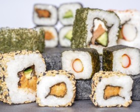 Various sushi dishes on dark grey stone surface