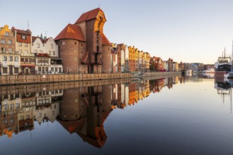 Waterfront promenade with reflection at sunrise in the Old Town, Brama Zuraw crane gate, Motlawa