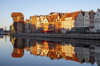 Waterfront promenade with reflection at sunrise in the Old Town, Brama Zuraw crane gate, Motlawa