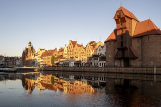 Waterfront promenade with reflection at sunrise in the Old Town, Brama Zuraw crane gate, Motlawa
