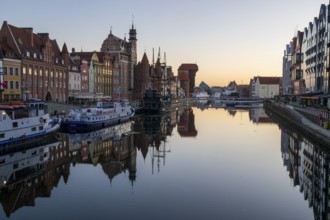 Waterfront promenade with reflection at sunrise in the Old Town, Brama Zuraw crane gate, Motlawa