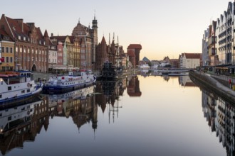 Waterfront promenade with reflection at sunrise in the Old Town, Brama Zuraw crane gate, Motlawa
