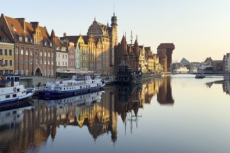 Waterfront promenade with reflection at sunrise in the Old Town, Motlawa River, Gdansk, Poland