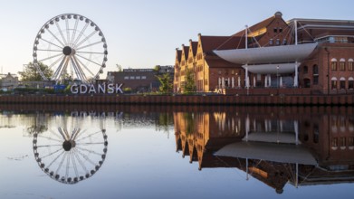 Ferris wheel on the waterfront with reflection at sunrise in the old town, Motlawa River, Gdansk,
