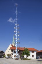 Parish Church of the Assumption of the Virgin Mary with maypole and town hall on the village