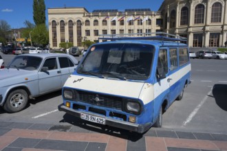 A blue van parked in front of a classic building under a clear sky, car RAF-2203 Latvija, nicknamed