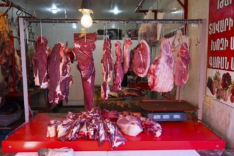 An illuminated market stall with raw meat and hangers, meat hanging open in the shop, Gyumri,