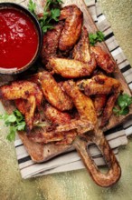Fried in the oven, chicken wings, with spices, tomato sauce, on a cutting board, gray background,