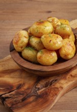Baked new potatoes, with butter and dill, on a wooden plate, homely, rustic, no people