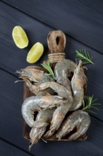 Fresh raw, white-footed shrimp, tiger prawns vannamei, on a wooden cutting board, with lime slices,