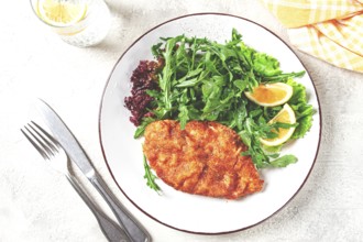 Milanese chicken, Crispy breaded chicken served, with fresh herbs, and lemon wedges