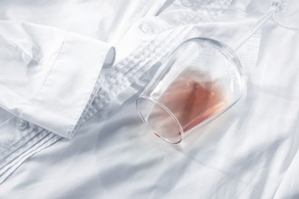 Glass, with pink wine, spilled on a white shirt, close-up, selective focus, no people, concept, top