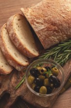 Sliced ciabatta, on a chopping board, with rosemary and olives, Italian bread, close-up, Italian