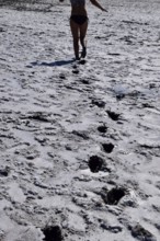 Woman walking along the dry bottom of a salt lake, rear view. Taman, Krasnodar Krai, Russia