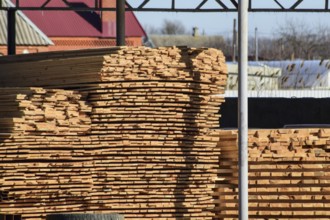 Warehouse of building materials, wood planks stacked under a canopy. Atyrau, Kazakhstan