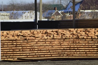 Warehouse of building materials, wood planks stacked under a canopy. Atyrau, Kazakhstan