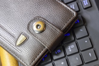 Brown wallet lying on a black computer keyboard. Atyrau, Kazakhstan