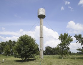 Silver Water Tower among green grass and trees. Atyrau, Kazakhstan