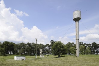 Silver Water Tower among green grass and trees. Atyrau, Kazakhstan