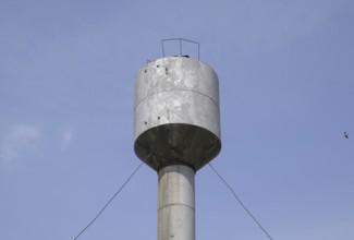 Silver Water Tower among green grass and trees. Atyrau, Kazakhstan