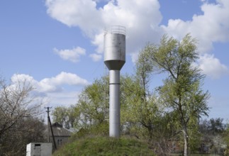 Silver Water Tower among green grass and trees. Atyrau, Kazakhstan