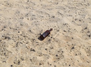 An empty bottle of beer is lying on the sand. Golubitskaya, Russia