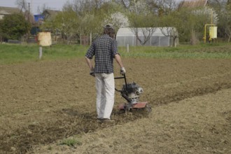 A man plows a tiller in the garden. Atyrau, Kazakhstan
