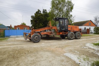 Grader on a dirt gravel road. Street repair by adding rubble. Krasnodar, Russia