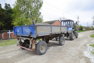 A tractor with a rubble cart for repairing the road. Feeding holes on the road. Krasnodar, Russia