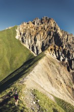 Hiker walking along narrow ridge trail at Kabarjina Mountain in Kazbegi National Park Georgia with
