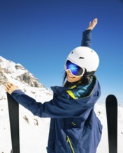 Young happy caucasian woman pose with skis arms outstretched in alpine zone. Get away skiing