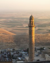 Historic Ulu Cami minaret in Mardin Turkey illuminated by sunset, overlooking ancient Mesopotamian