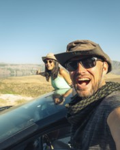 Happy travelers on summer road trip with rental car, symbolizing freedom, travel insurance, car