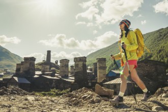 Traveler hiking with backpack and poles in Ushguli, Svaneti mountains, wellness trekking and
