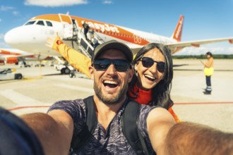 Milan, Italy - 12th august, 2025: happy smiling couple taking selfie in front of EasyJet airplane