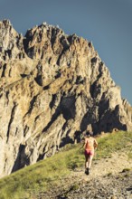 Sporty Female athlete trail runner running in motion mid air in alpine mountains, adventure fitness