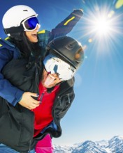 Happy young caucasian skiers couple in love having fun together playing in mountains piggybacking