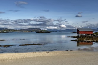 Red Hut Cottage And White Sand Beach On Sommaroy Island At Calm Fjord In Norway