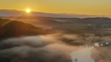 The morning dawns, the sun rises slowly over the river. A gentle mist hangs over the water and the