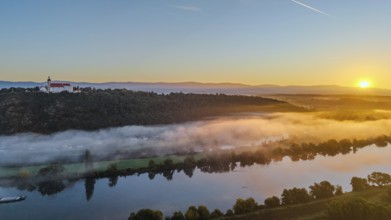 The sunrise bathes the Danube in warm light. A light mist hovers over the water, while the