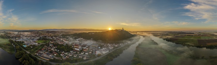 The sun rises over a city surrounded by fog. The picture shows the river landscape of the Danube
