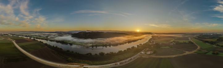 The sunrise lights up the Danube as the mist hovers over the water. Gentle hills and green fields