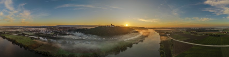 The sunrise shines over the Danube valley. Mist hovers over the river, while the rolling hills and