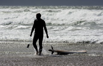 Silhouette Of A Surfer With His Surfboard Leaving Water Of Cold Atlantic At The Coast Of Ireland