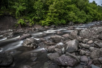 Long-Time Exposed Wild Mountain River Streaming Through Green Forest in Scotland, United Kingdom