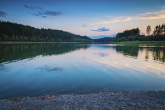 Reflecting water in the reservoir against an evening forest backdrop and a peaceful atmosphere,