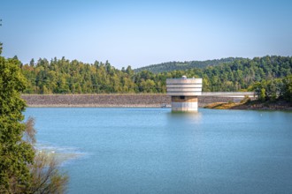 Round tower at the dam wall in the reservoir with surrounding forest and blue sky, Zeulenrodaer