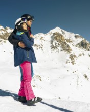 Young caucasian couple pose hug enjoying looking at snowy mountains range in winter. Get away
