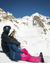 Young caucasian couple pose sits hug enjoying looking at snowy mountains in winter. Get away skiing